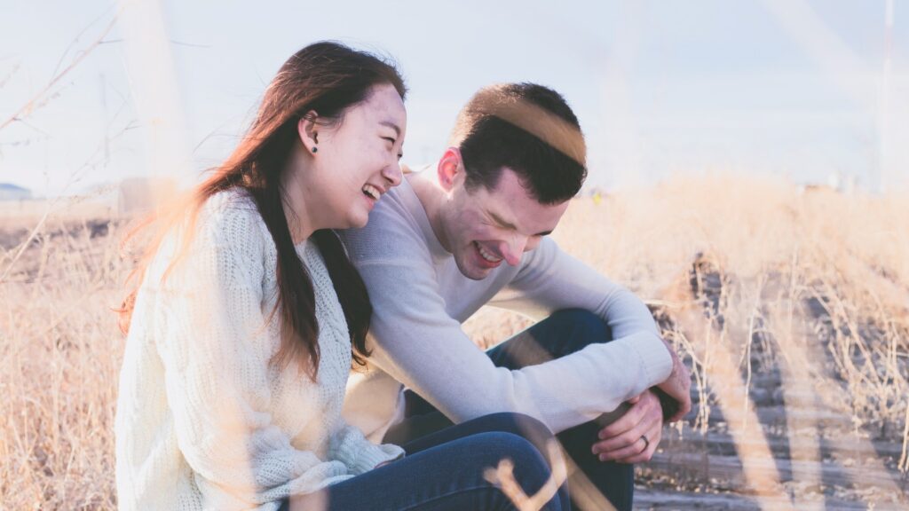 young couple sitting and laughing together in a field, Friendship, Valentine's Day