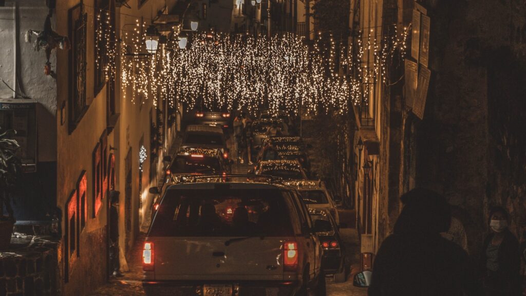 Photo of a small Mexican town during the holidays with lights covering the streets filled with cars and people